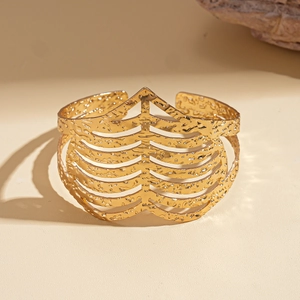 Detailed macro view of wide open gold bangle with textured hammered finish and hollow design
