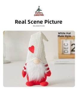 Close-up of a Christmas gnome doll with a white knitted heart hat on a wooden desk