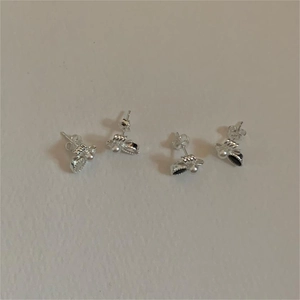 Detailed view of silver bow-knot bee stud earrings with white pearl accents and zircon