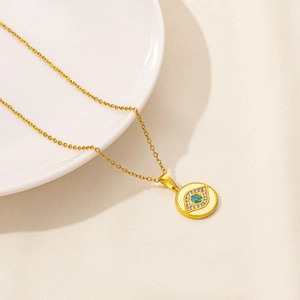 Detail of gold evil eye pendant with blue crystals on a white ceramic plate