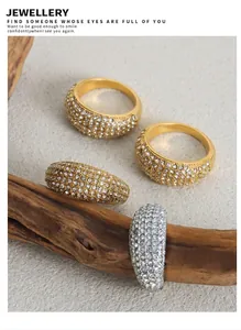 Detailed view of luxury dome rings with pave set cubic zirconia on wooden backdrop
