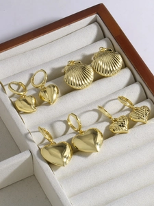 Dettaglio di orecchini a cuore e conchiglia placcati oro 18k in una scatola di velluto di lusso