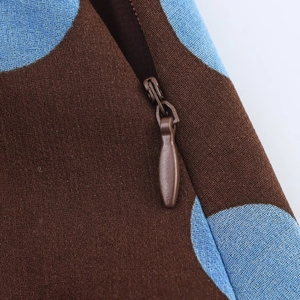 Macro shot of invisible zipper detail on blue and brown polka dot asymmetrical top