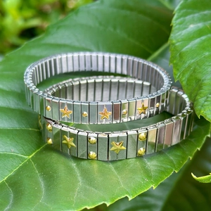 Minimalist stainless steel elastic bracelets with gold stars on green leaves