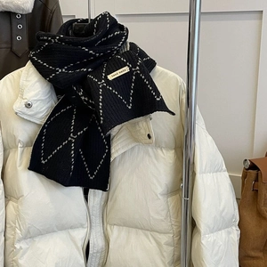Detail of black knit scarf featuring white diamond patterns and handmade tag label