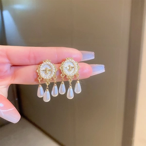 Detail of vintage gold bee earrings featuring pearl frame and dangling pearl teardrops