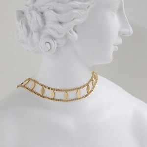 Detailed close-up of a double-layered gold geometric rhombus choker on a classical statue