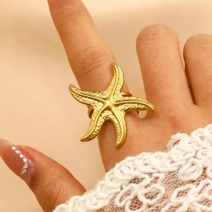 Gold starfish ring in stainless steel worn on hand with white lace sleeve detail