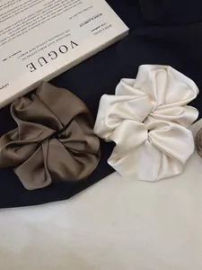 Close-up of oversized coffee and cream satin scrunchies showing smooth silk texture