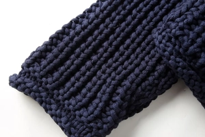 Détail macro de la texture en grosse maille bleu marine sur un pull tendance