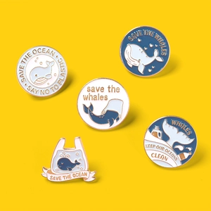 Detailed set of five blue enamel whale and eco-friendly pins on a bright yellow background