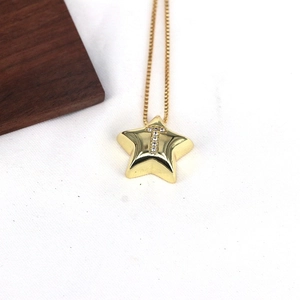 Detailed macro view of a gold star pendant with letter T inlay and clear zircons