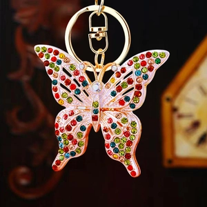 Close-up of golden butterfly keychain with colorful sparkling rhinestones on dark background