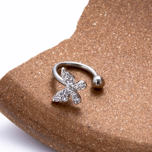 Vue macro d'un piercing papillon argenté avec zircons sur une pierre texturée