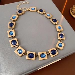 Vue détaillée du collier vintage doré avec maillons carrés et pierres bleues