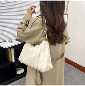 Detail of white plush shoulder bag featuring soft pleated faux fur and golden ring hardware