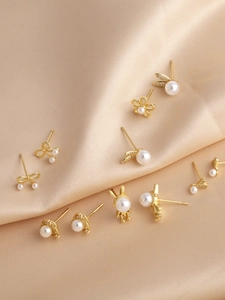 Détail d'un lot de boucles d'oreilles dorées avec perles, motifs lapin, nœud et fleur