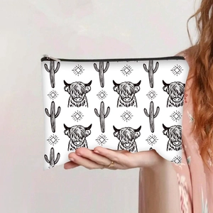 Detail of Highland Cow print canvas makeup bag held by hand with black zipper closure