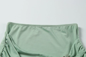 Detail of light green ruched dress with metal ring ornament and premium knitted fabric