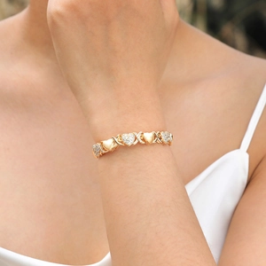 Close-up of a gold heart bracelet with cubic zirconia and XO design on a woman's wrist