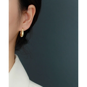 French style minimalist gold drop earring worn by a model in a clean studio setting