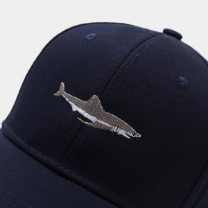 Close-up of navy blue cotton baseball cap featuring detailed shark embroidery and eyelets