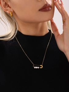 Détail d'un collier épingle à nourrice doré avec perles et boucles d'oreilles assorties