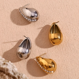 Detail of teardrop earrings with gold and silver finish and zircon stones on stone