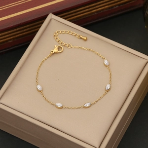Elegant gold chain bracelet featuring five oval white gemstones on a beige jewelry box