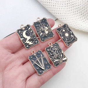 Detailed close-up of tarot card enamel charms showing moon and stars in black and gold finish
