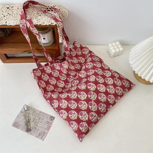 Close-up of red floral canvas tote bag featuring small flower prints and brand woven label