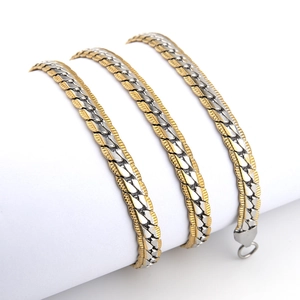 Detailed view of tricolor gold silver and bronze flat curb chain coiled on a white stand