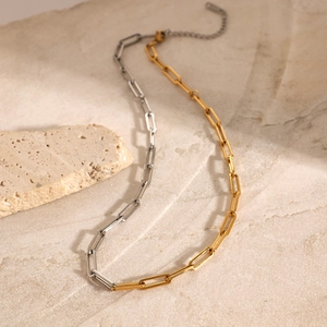 Two-tone gold and silver stainless steel paperclip chain necklace on stone surface