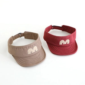 Detail of adjustable sun visor caps with embroidered M logo in khaki and red colors