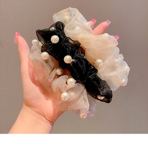 Close-up of organza scrunchies with white pearls in black and champagne colors