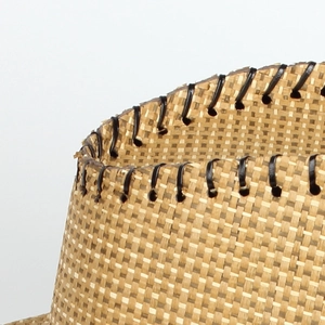 Macro shot of fine cross-weave straw sun hat brim with black leather reinforced edge