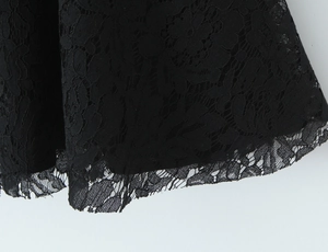 Macro detail of black lace dress hem featuring floral patterns and eyelash trim finish