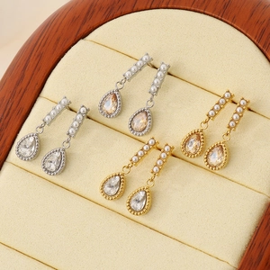 Détails de boucles d'oreilles goutte avec zircons et perles dans un écrin en bois