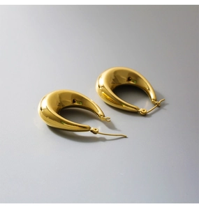 Macro shot of thick gold-plated U-shaped earrings with a high-shine polished metal finish