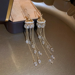 Detailed close-up of golden tassel earrings with crystal water drop charms on a tray