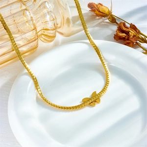 Elegante collana a farfalla dorata con catena a lama su un vassoio bianco decorativo