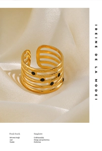 Detail of golden five-layered open ring with black enamel dots on silk fabric