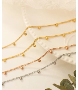 Detail of beaded metal chains in gold, rose gold and silver finishes on lace