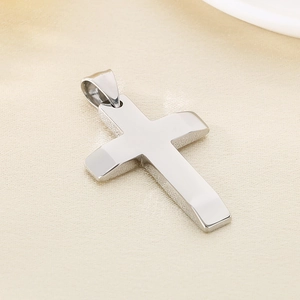 Macro shot of polished silver stainless steel cross pendant on textured fabric