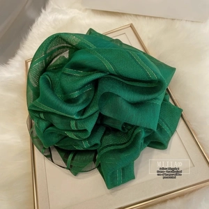 Detailed close-up of emerald green silk wool scarf with subtle gold metallic stripes