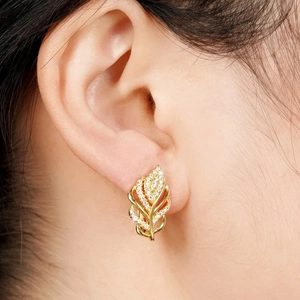 Elegant gold leaf wheat ear earrings with white zircon crystals on a model's ear