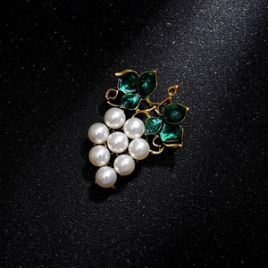 Elegant gold alloy grape brooch with white pearls and green enamel on a black luxury base