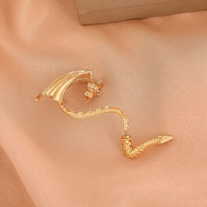 Exquisite gold dragon ear cuff with detailed scales and wings on silk background