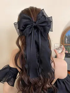 Detail of elegant black mesh oversized bow hair clip with long ribbons worn by a woman