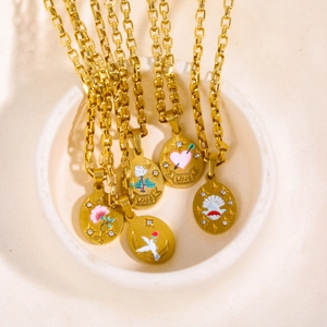 Detail of five gold stainless steel necklaces with hand-painted enamel charms in a ceramic bowl